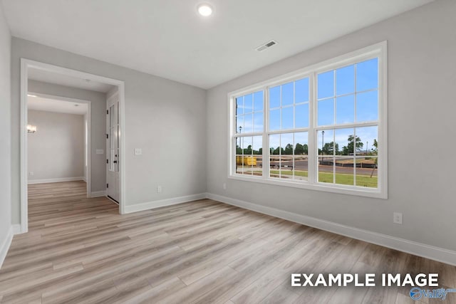 unfurnished room with light wood-style flooring, baseboards, and visible vents