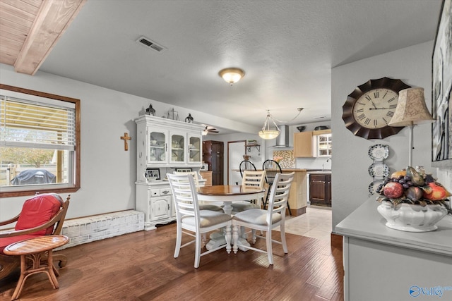 dining room featuring beam ceiling, hardwood / wood-style flooring, a textured ceiling, and sink