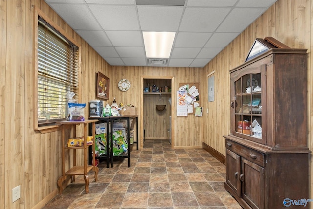 interior space featuring a drop ceiling and wood walls