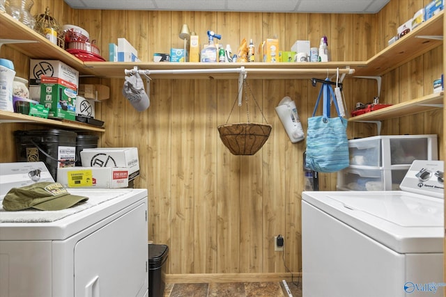 clothes washing area with washer and clothes dryer and wood walls