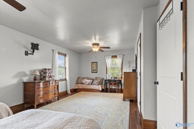 bedroom with multiple windows, dark hardwood / wood-style floors, a textured ceiling, and ceiling fan