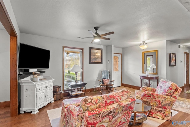 living room featuring light hardwood / wood-style flooring, a textured ceiling, and ceiling fan