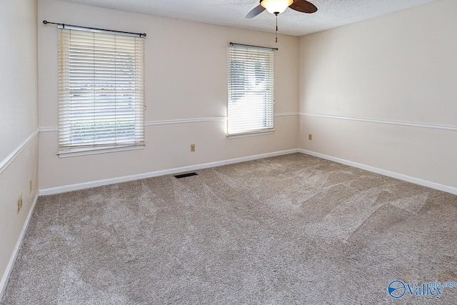 empty room with ceiling fan, light colored carpet, and a textured ceiling