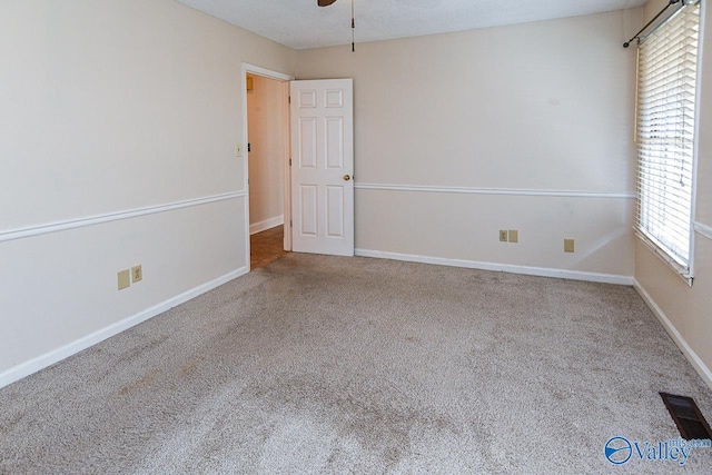 carpeted spare room featuring ceiling fan and a healthy amount of sunlight