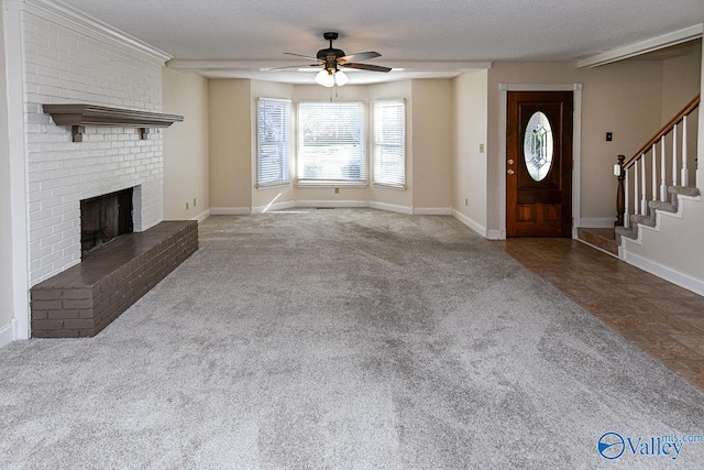 unfurnished living room with carpet flooring, ceiling fan, a textured ceiling, and a brick fireplace