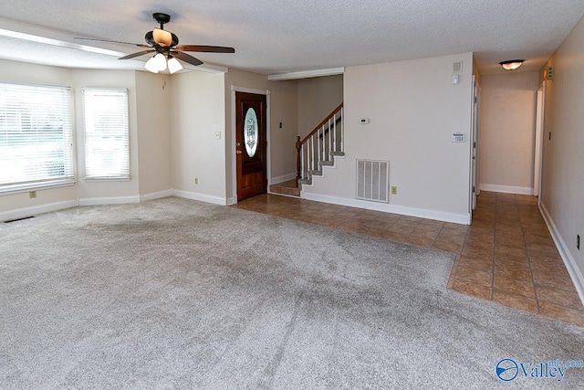 unfurnished living room featuring carpet, a textured ceiling, and ceiling fan