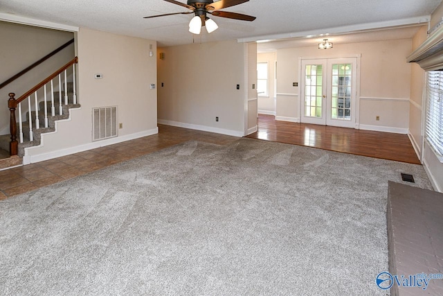 unfurnished living room with ceiling fan, french doors, dark carpet, and a textured ceiling