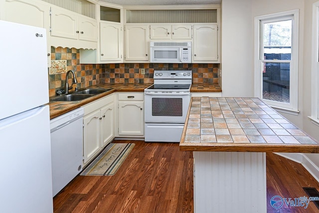 kitchen with tasteful backsplash, white appliances, sink, and dark wood-type flooring