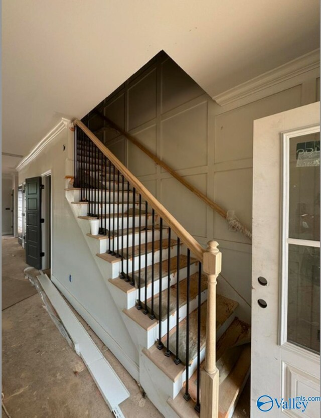 stairway featuring concrete flooring and ornamental molding