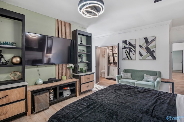 bedroom featuring crown molding, ensuite bathroom, and light wood-style flooring