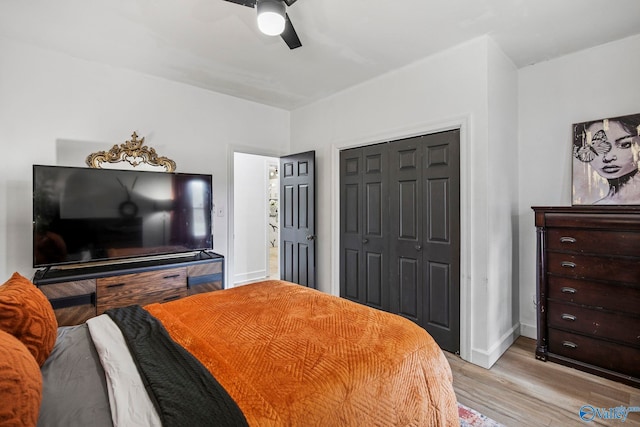 bedroom featuring light wood-style flooring, a closet, baseboards, and a ceiling fan