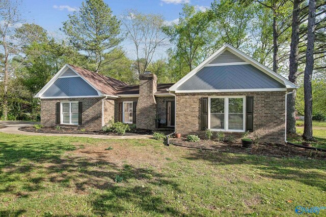 view of front of house with a chimney, a front yard, and brick siding