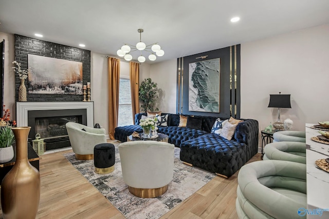 living area featuring a large fireplace, recessed lighting, an inviting chandelier, and wood finished floors