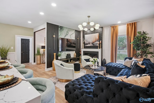 living area with a chandelier, a fireplace, recessed lighting, and wood finished floors