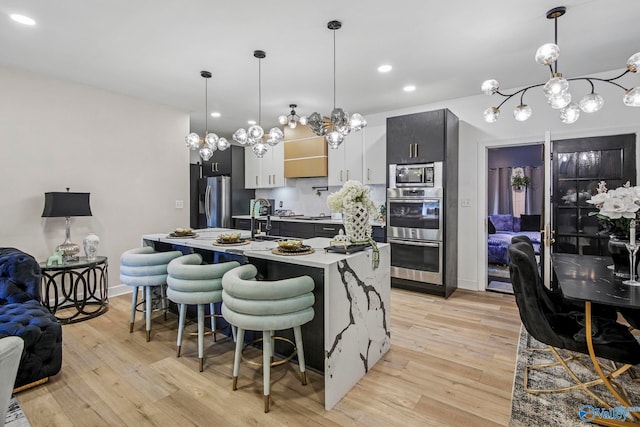 kitchen featuring light wood-type flooring, recessed lighting, light countertops, hanging light fixtures, and stainless steel appliances