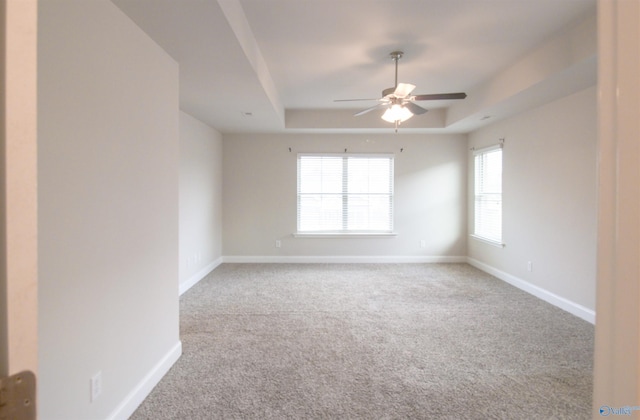 carpeted empty room featuring ceiling fan and a tray ceiling