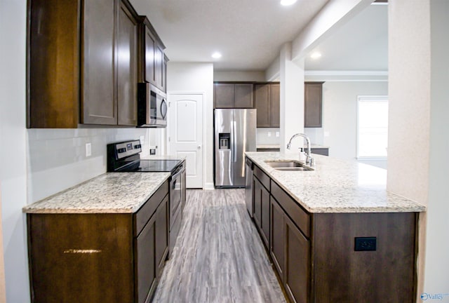 kitchen featuring sink, stainless steel appliances, light stone counters, tasteful backsplash, and light hardwood / wood-style floors