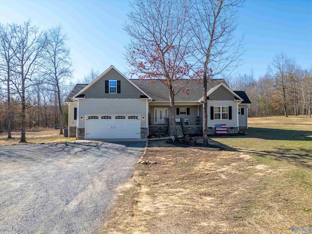 craftsman-style home featuring covered porch, driveway, stone siding, and a front yard