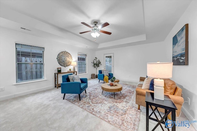 living room with carpet flooring, a raised ceiling, and ceiling fan