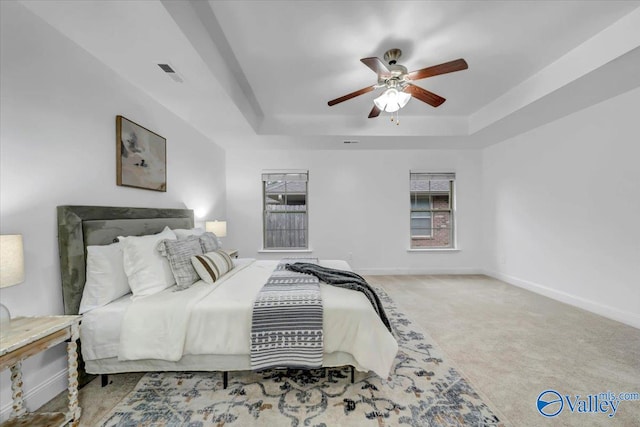 bedroom with ceiling fan, carpet floors, and a tray ceiling