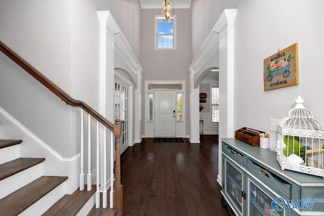 foyer featuring dark wood finished floors, stairway, a chandelier, and a high ceiling