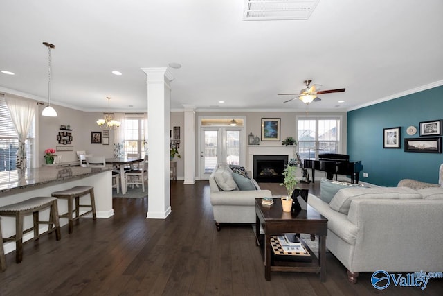 living room with dark wood-style floors, visible vents, ornate columns, and a healthy amount of sunlight