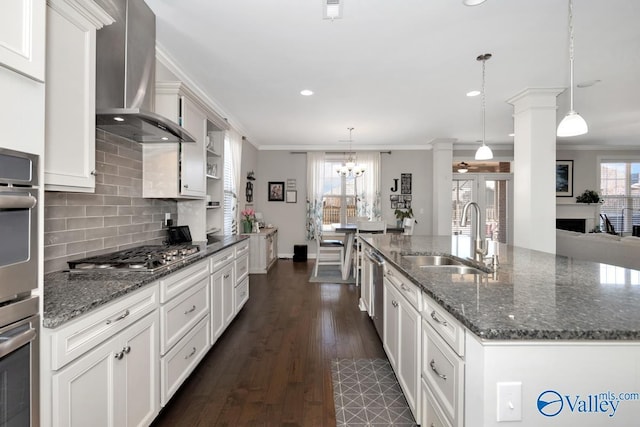 kitchen with a sink, wall chimney exhaust hood, ornamental molding, and ornate columns