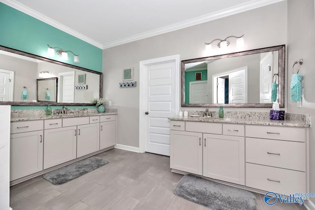 bathroom featuring ornamental molding, two vanities, baseboards, and a sink