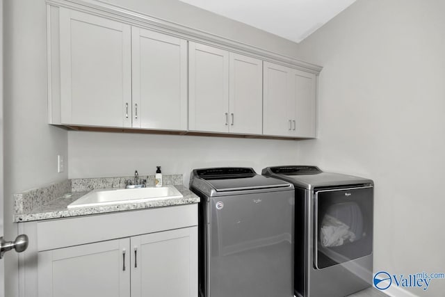 washroom with a sink, cabinet space, and independent washer and dryer