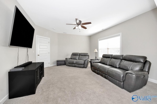 living area featuring light colored carpet, baseboards, and ceiling fan