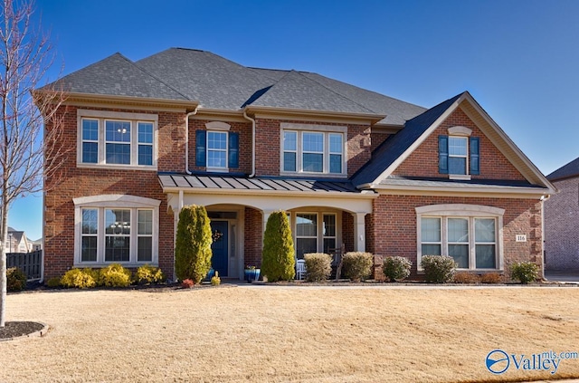 view of front of property featuring metal roof, brick siding, roof with shingles, and a standing seam roof