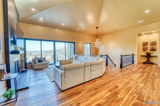 living room with visible vents, light wood finished floors, and an inviting chandelier