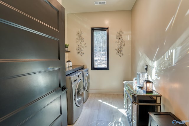 laundry room with laundry area, light wood finished floors, visible vents, baseboards, and independent washer and dryer