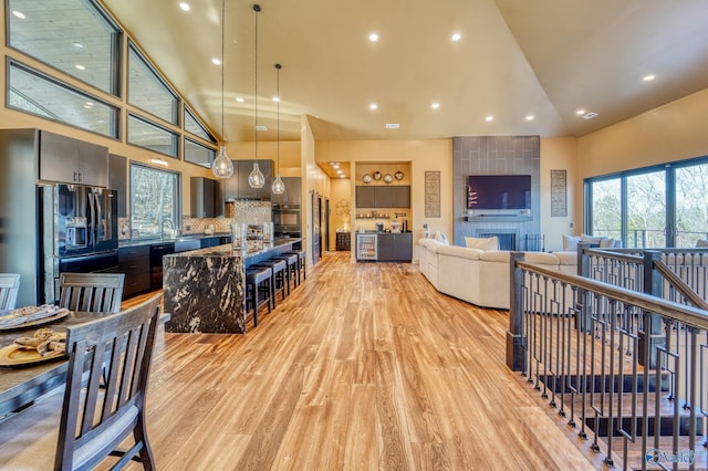 interior space featuring light wood-style floors, a tile fireplace, high vaulted ceiling, and recessed lighting