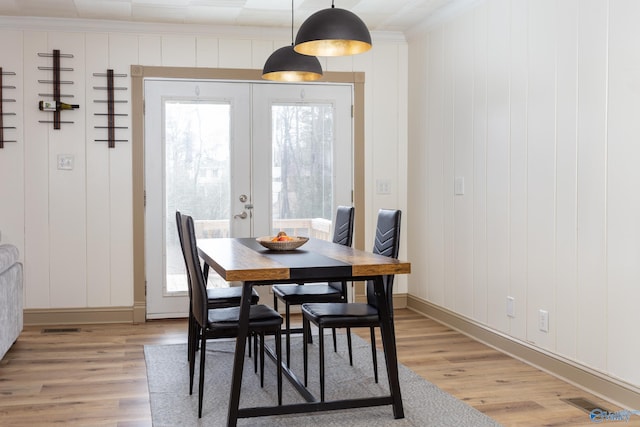 dining room featuring light wood-style floors, french doors, and crown molding