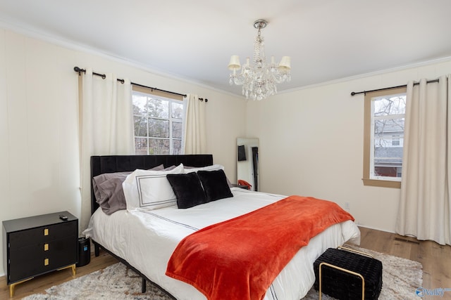 bedroom featuring ornamental molding, multiple windows, an inviting chandelier, and wood finished floors