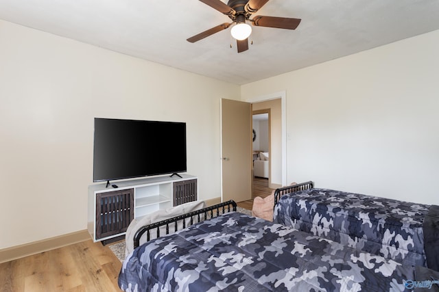 bedroom featuring a ceiling fan, baseboards, and wood finished floors