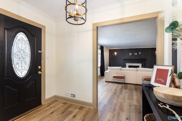 entrance foyer featuring visible vents, light wood-style flooring, crown molding, a fireplace, and a wealth of natural light