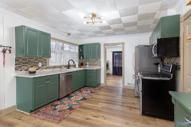 kitchen featuring light wood-style flooring, stainless steel appliances, a sink, open shelves, and crown molding