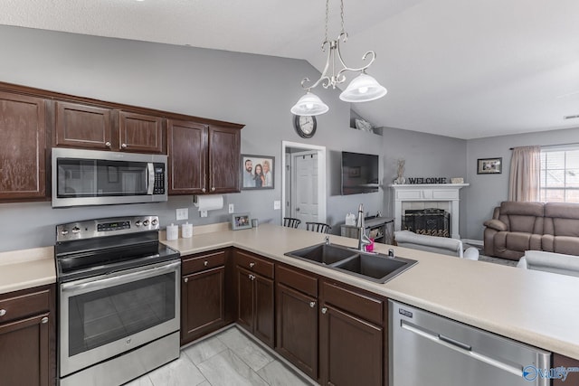 kitchen featuring pendant lighting, lofted ceiling, sink, kitchen peninsula, and stainless steel appliances