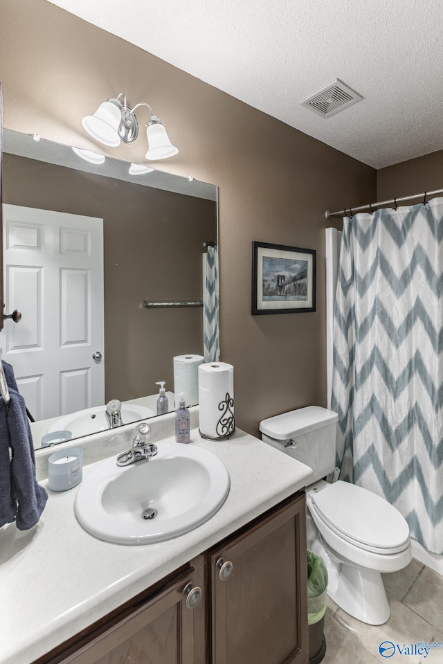 bathroom featuring vanity, tile patterned floors, a textured ceiling, and toilet