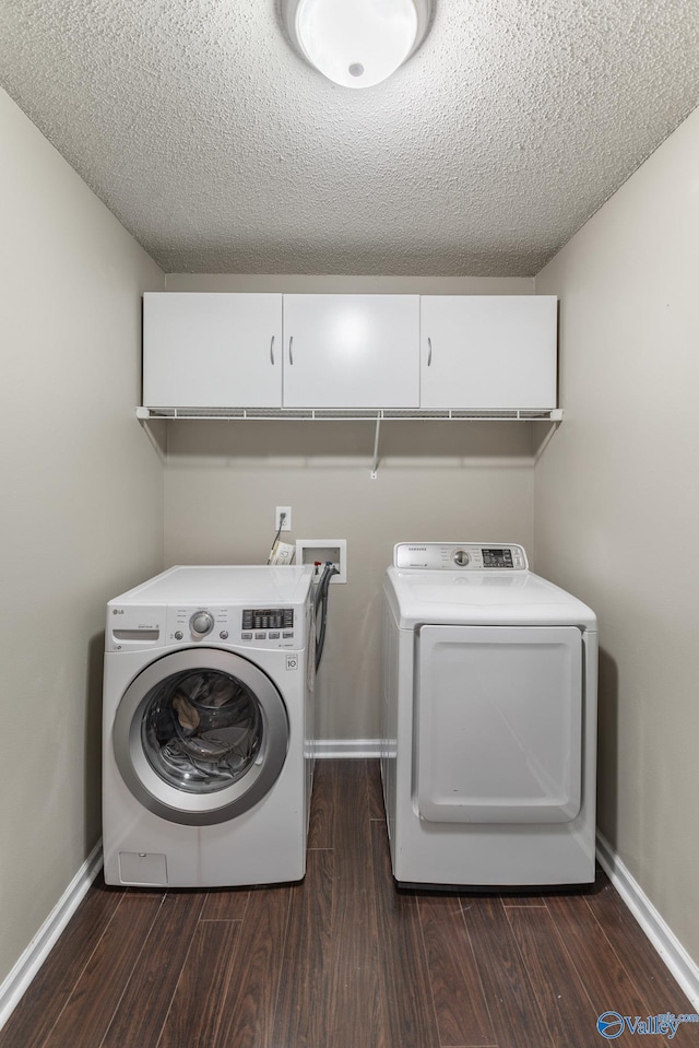 laundry area with cabinets, separate washer and dryer, a textured ceiling, and dark hardwood / wood-style flooring