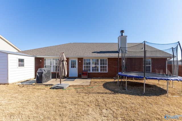 back of house with a patio, a yard, and a trampoline