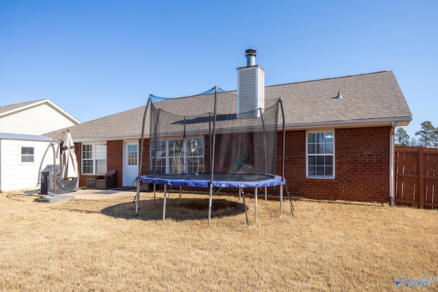 back of property featuring a trampoline, a patio area, and a lawn