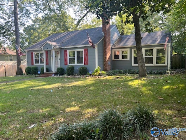 view of front of property with a chimney, fence, and a front lawn