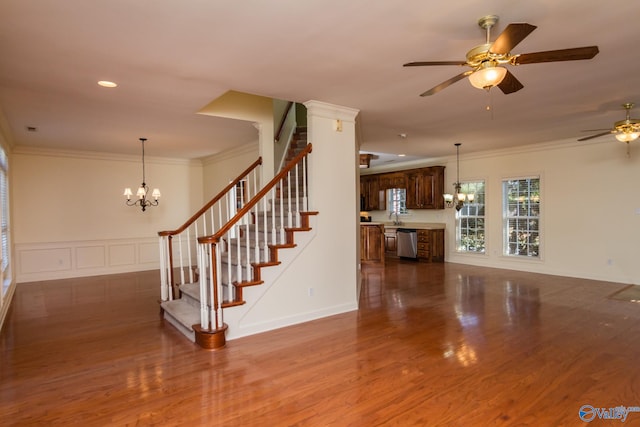 unfurnished living room with ceiling fan with notable chandelier, hardwood / wood-style flooring, and ornamental molding