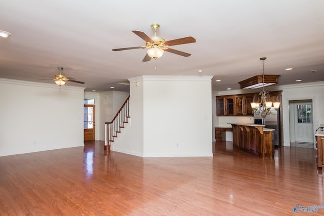 living room with ornamental molding, ceiling fan with notable chandelier, and hardwood / wood-style flooring