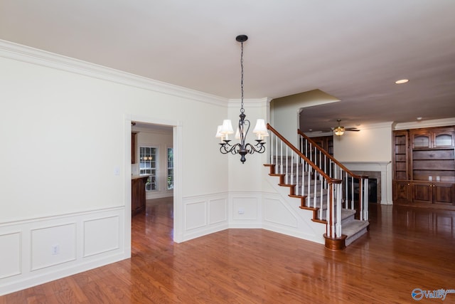 unfurnished dining area with hardwood / wood-style floors, ceiling fan with notable chandelier, and ornamental molding