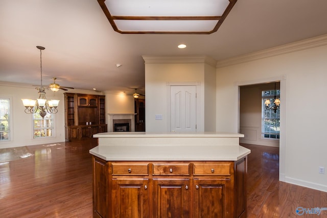 kitchen with dark hardwood / wood-style floors, a kitchen island, hanging light fixtures, and crown molding