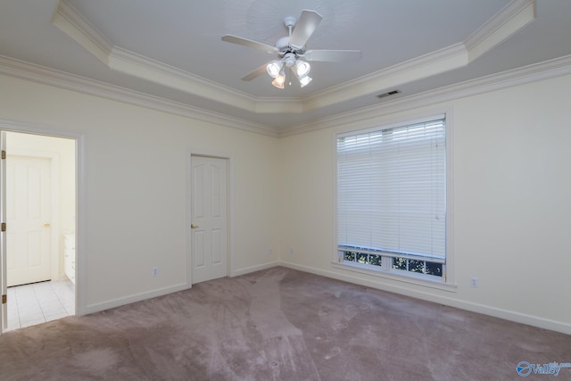 carpeted spare room with ceiling fan, a raised ceiling, and crown molding